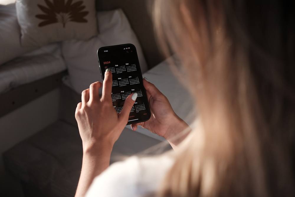 Personne tenant un smartphone affichant un calendrier de l'année 2024.