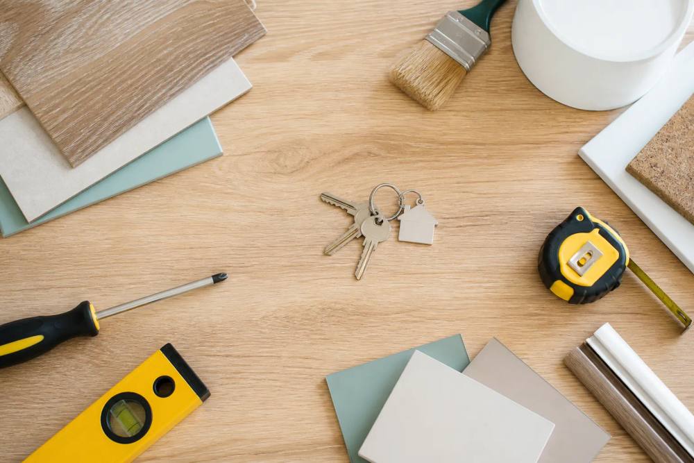 Outils et matériaux de rénovation sur un plancher en bois.
