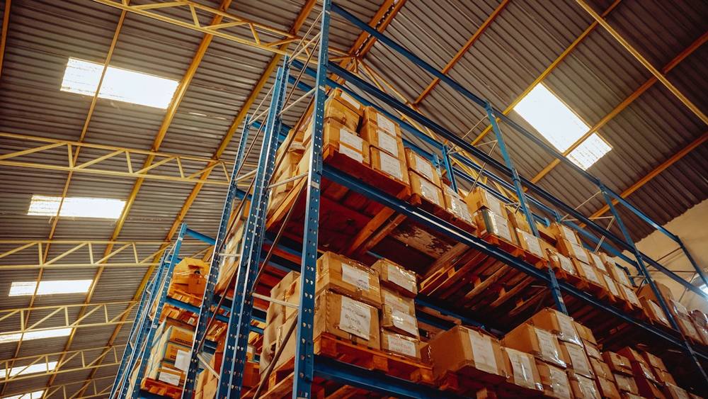 Entrepôt industriel avec étagères métalliques chargées de boîtes en carton.