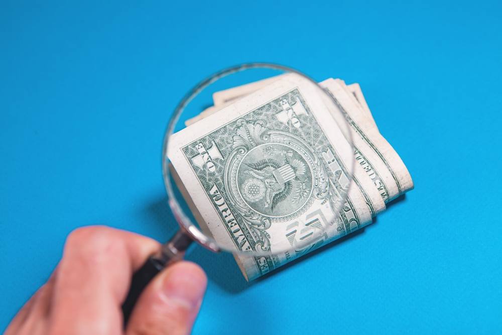 Loupe sur des billets de un dollar américain sur fond bleu.