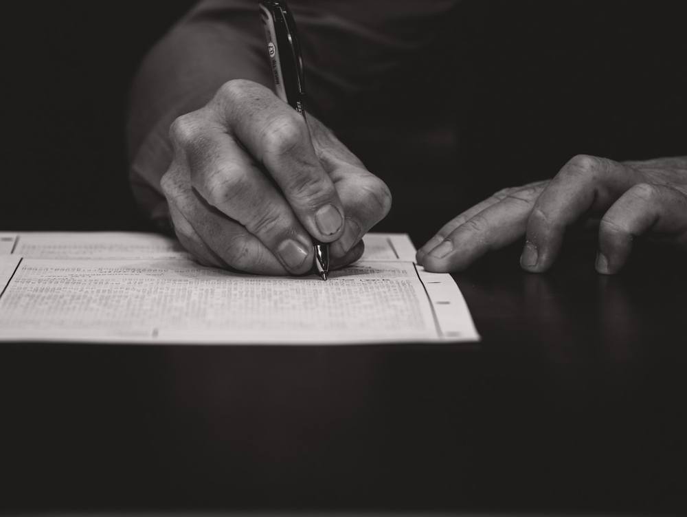 Mains écrivant avec un stylo sur un document.