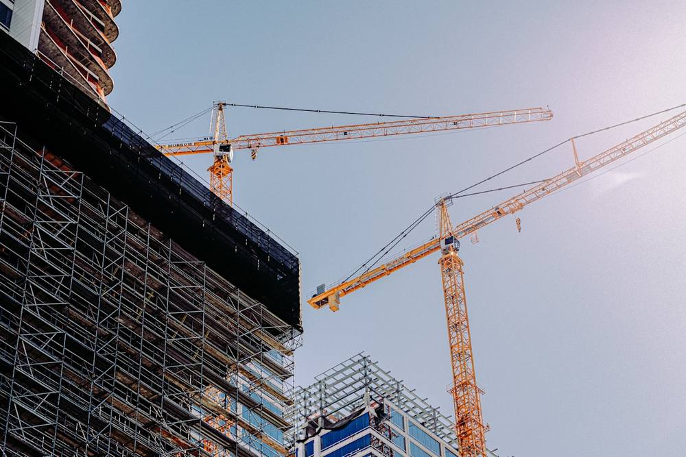 Chantier de construction avec grues et échafaudages métalliques.