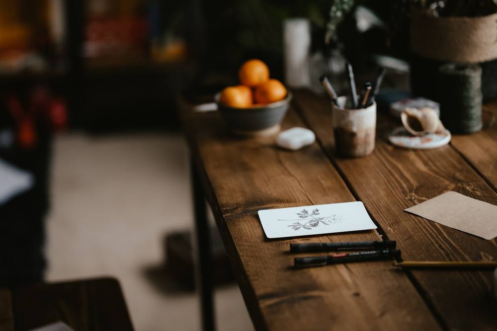 Espace de travail rustique avec fruits, outils et papiers sur une table en bois.