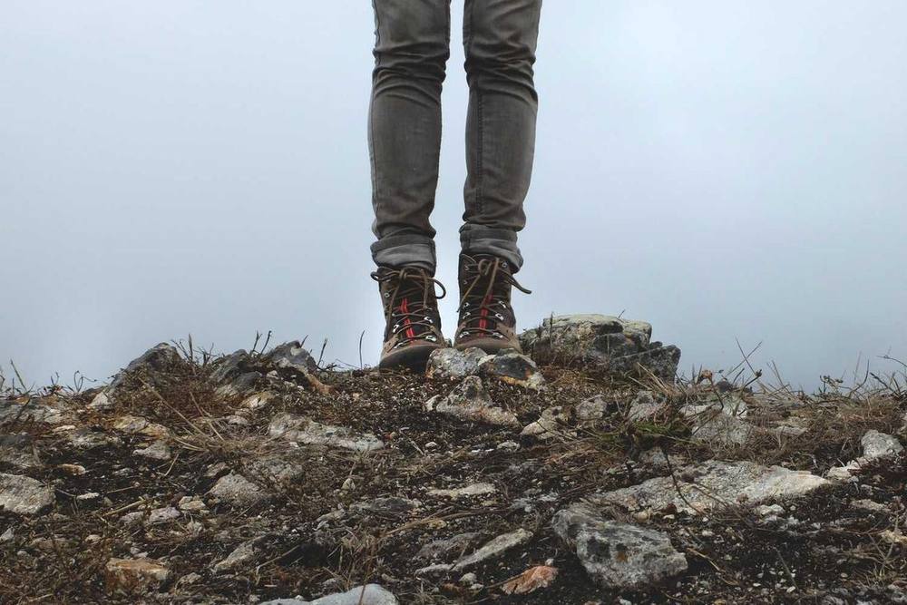 Une personne portant des bottes de randonnée se tient sur un sol rocheux.