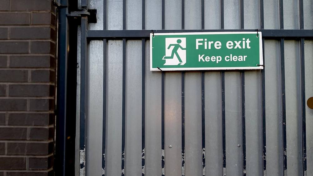Panneau de sortie de secours vert avec pictogramme de personne.