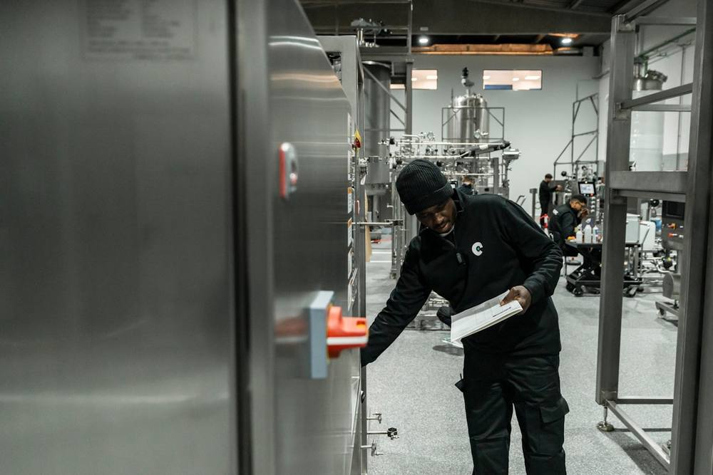 Homme en uniforme noir travaillant dans un laboratoire industriel.