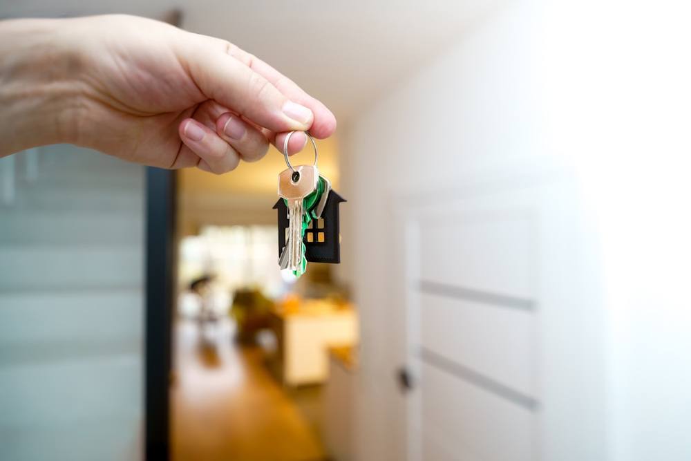 Clé de maison suspendue dans la main d'une personne.