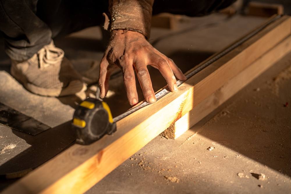 Un homme utilise une scie circulaire pour couper un morceau de bois.