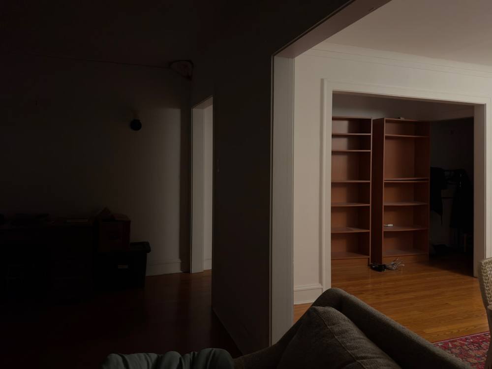 Vue intérieure d'une pièce faiblement éclairée avec des étagères de livres.