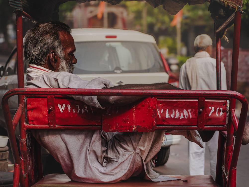 Un homme assis dans un rickshaw rouge dans une rue.