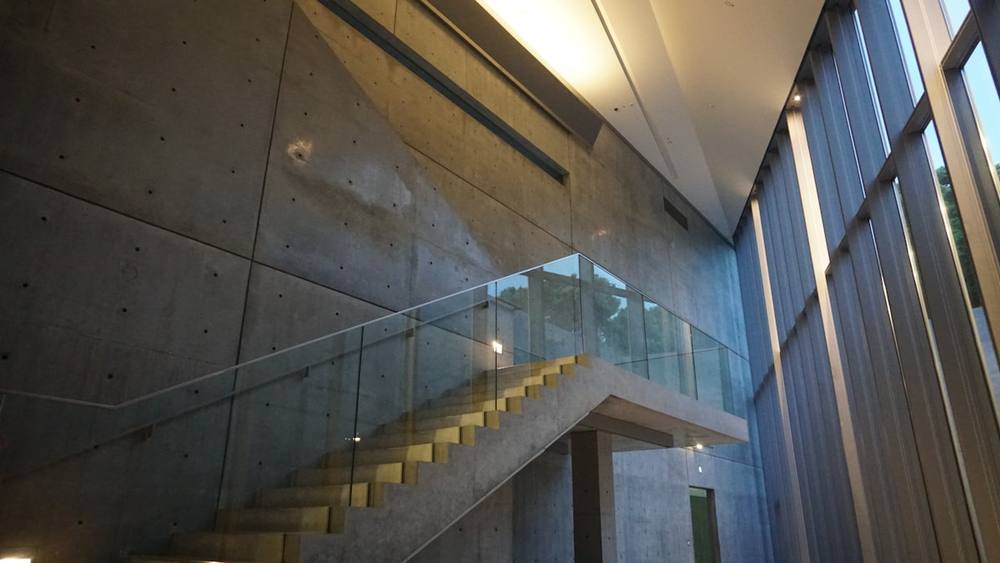 Escalier en béton avec garde-corps en verre dans un bâtiment moderne.