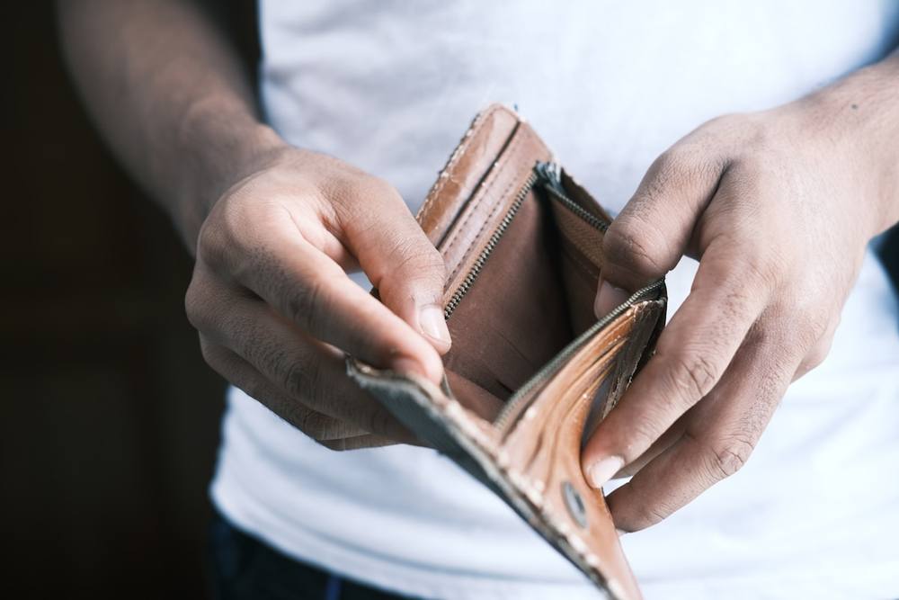Une personne tenant un portefeuille en cuir marron.
