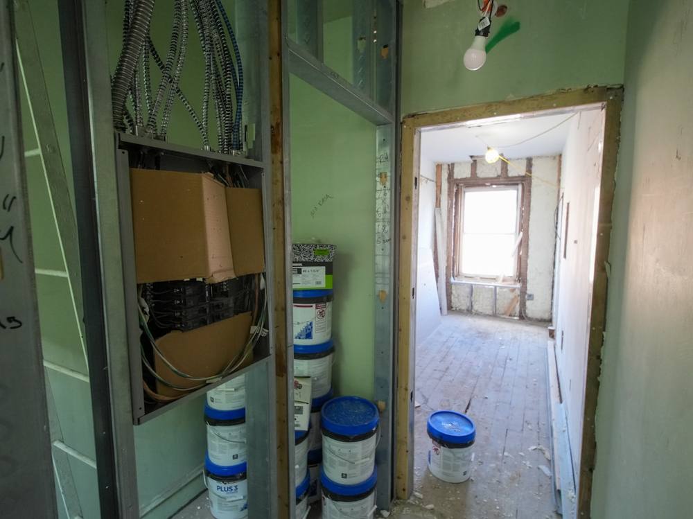 Intérieur en rénovation avec câbles électriques, boîtes et seaux de peinture.
