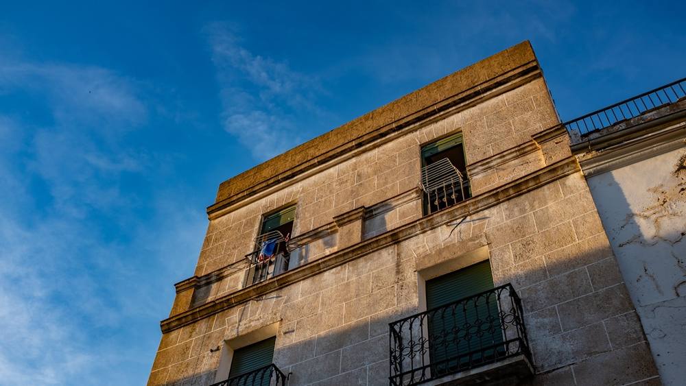 Bâtiment ancien en pierre avec balcons et fenêtres.