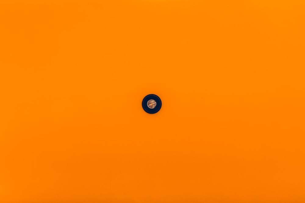 Bouton noir sur fond orange vif.