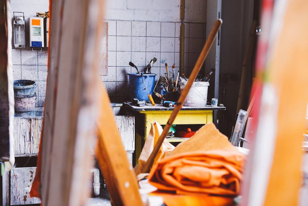 Atelier de peinture encombré avec des outils et des toiles.