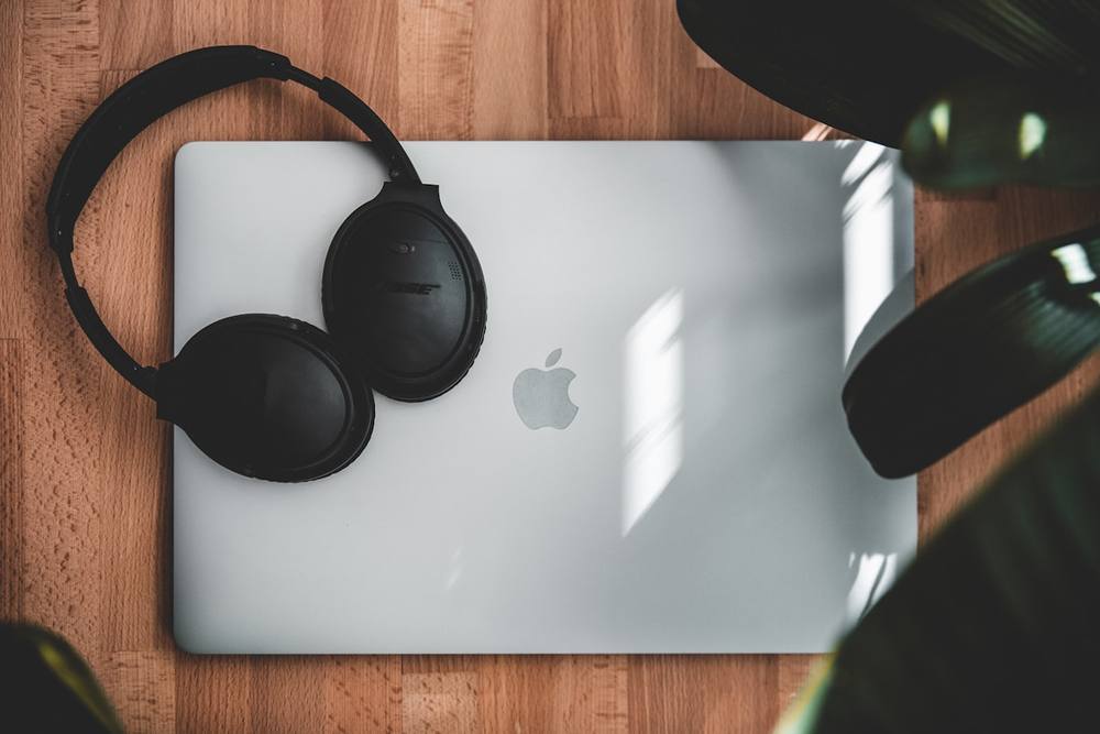 Ordinateur portable Apple avec casque audio Bose sur un bureau en bois.
