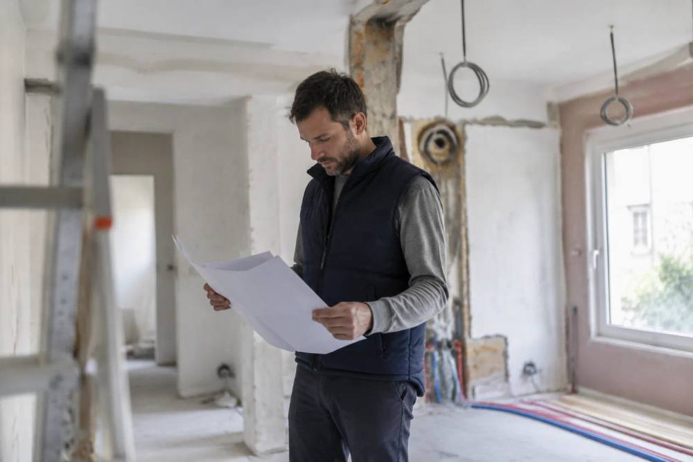Homme consultant des plans dans un appartement en rénovation