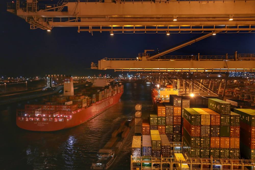 Port maritime animé la nuit, avec des grues et des conteneurs.