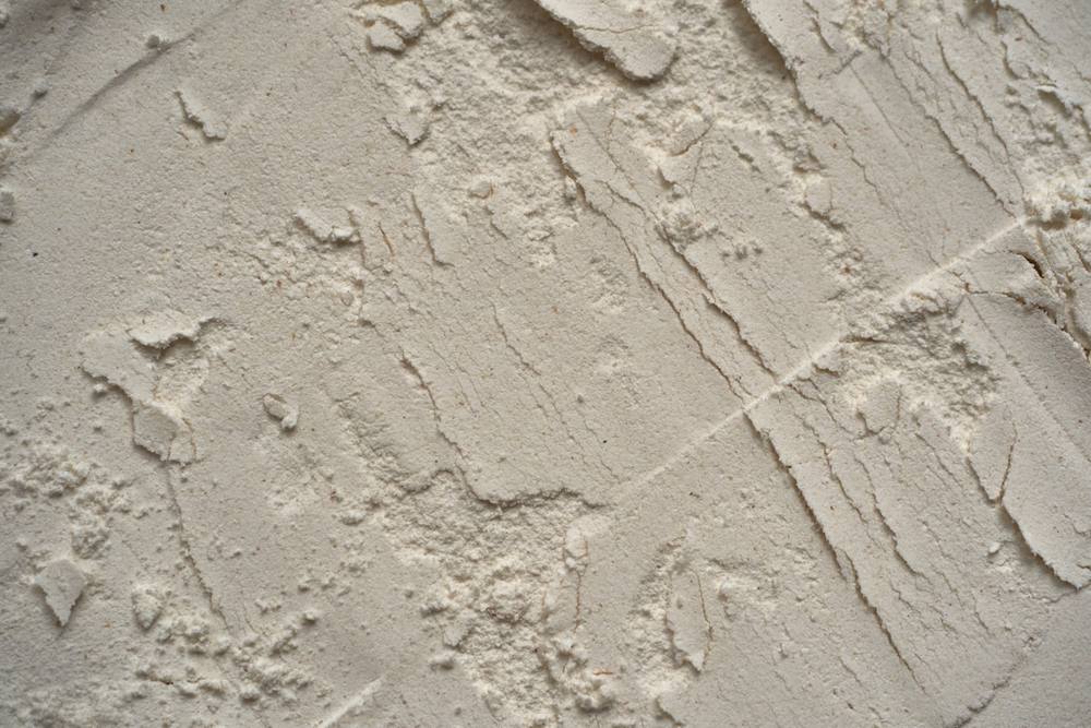 Texture de surface en plâtre craquelé et irrégulière.