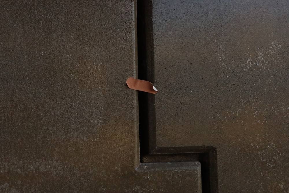 Clou rouillé sur un mur de béton texturé.