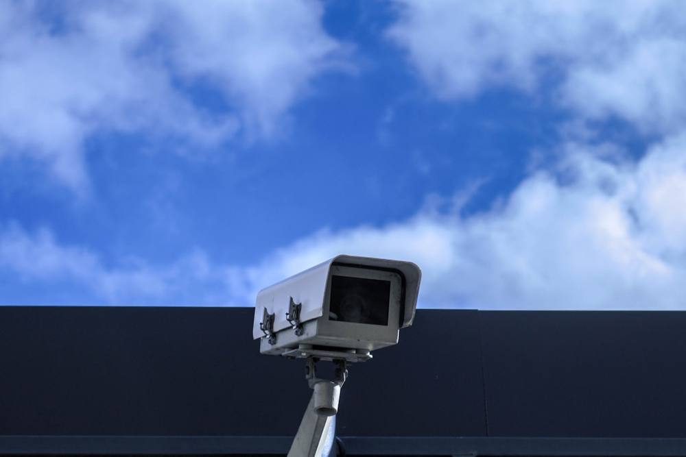 Caméra de surveillance montée sur un poteau contre un ciel nuageux.