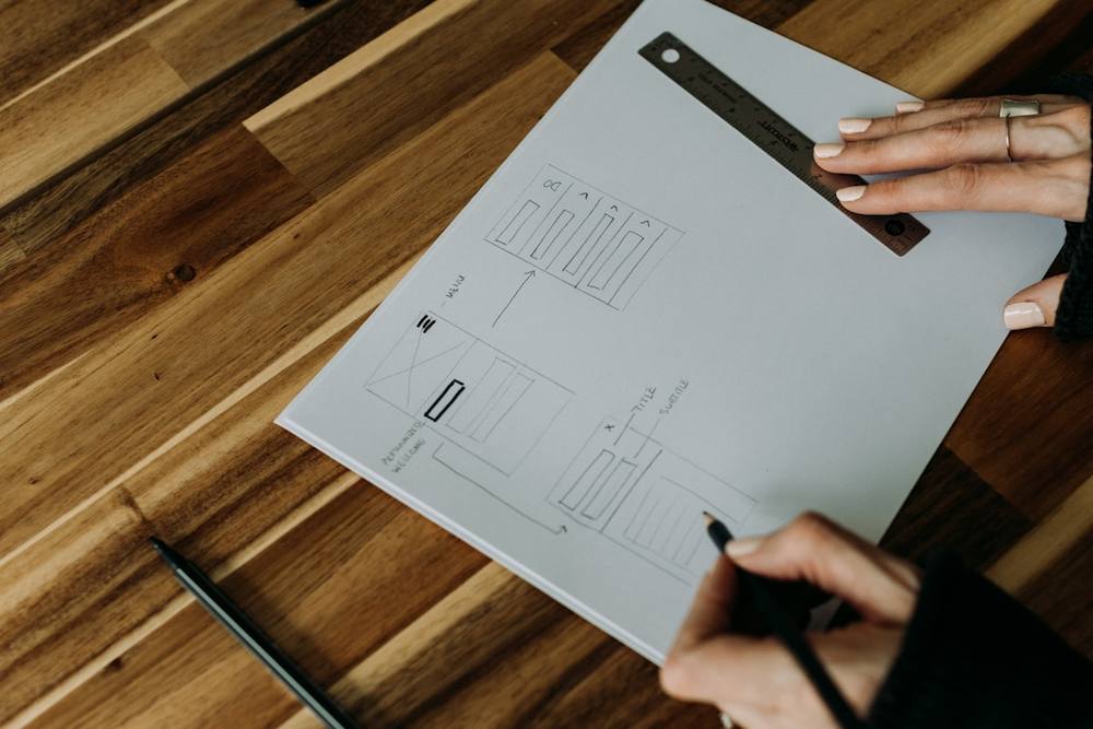 Une personne tenant un stylo au-dessus d'une feuille de papier.