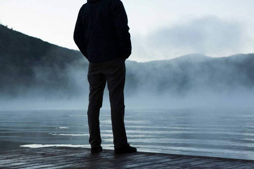 Personne sur un quai contemplant un lac brumeux.