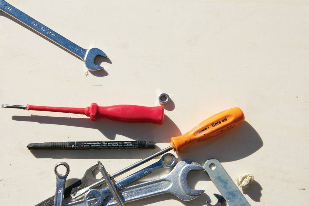 Outils métalliques, tournevis et feutre disposés sur une table blanche