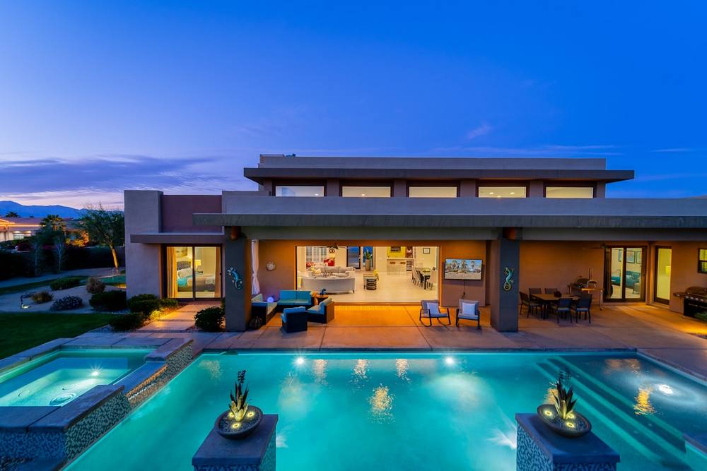 Maison de luxe avec piscine éclairée, terrasse et jardin paysager.