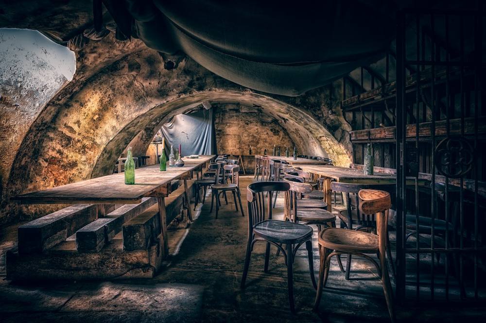 Intérieur rustique d'un bar souterrain avec tables en bois et chaises.
