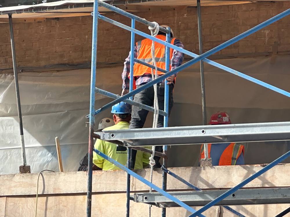 Deux hommes debout sur un échafaudage.