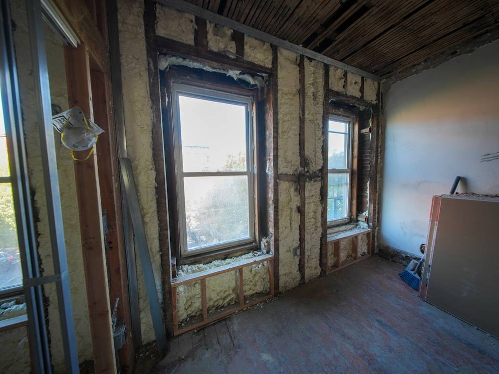 Intérieur délabré d'un bâtiment en rénovation, avec fenêtres endommagées et murs décrépis.
