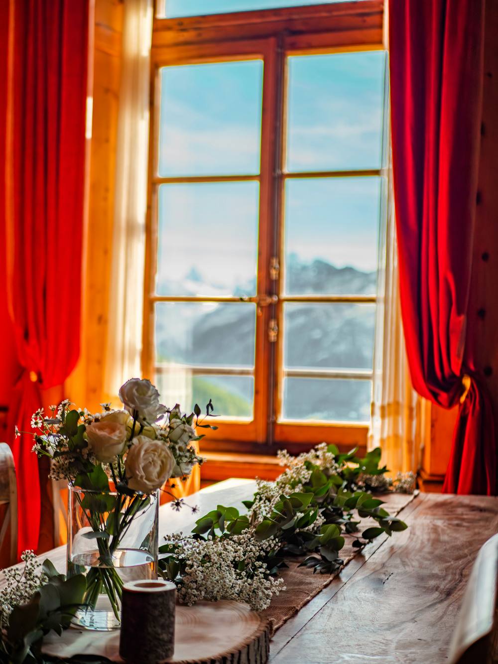 Une chambre à coucher moderne et minimaliste avec un sol en bois et une grande fenêtre avec vue sur les Alpes suisses.