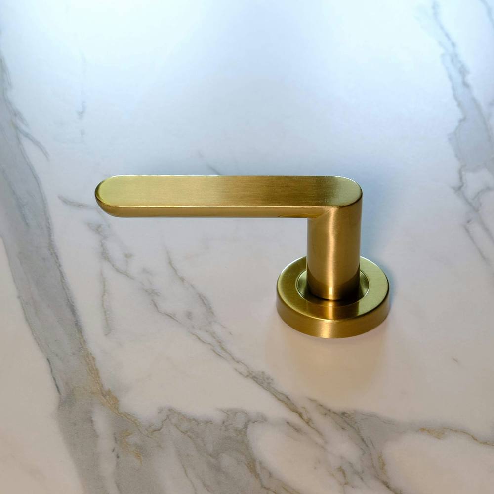 Gros plan sur la texture de marbre de haute qualité et le robinet doré dans une rénovation de salle de bain de luxe.
