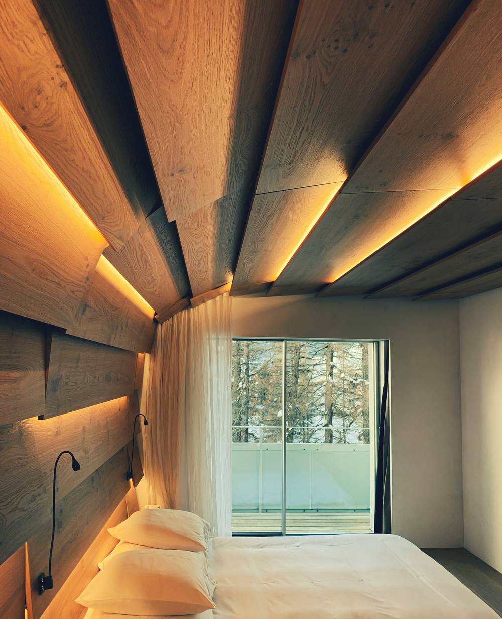 Intérieur de design avec mur de pierre éclairé par des spots encastrés au sol dans une maison de luxe suisse.